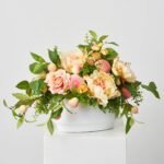 Feeling Peachy Queen - Peach Peonies & Roses, Real Touch Green Salal Leaf, Yellow Pink Ranunculus & Fuzzy Peaches Spring Summer Centerpiece Arrangement in White Concrete Oval Pot