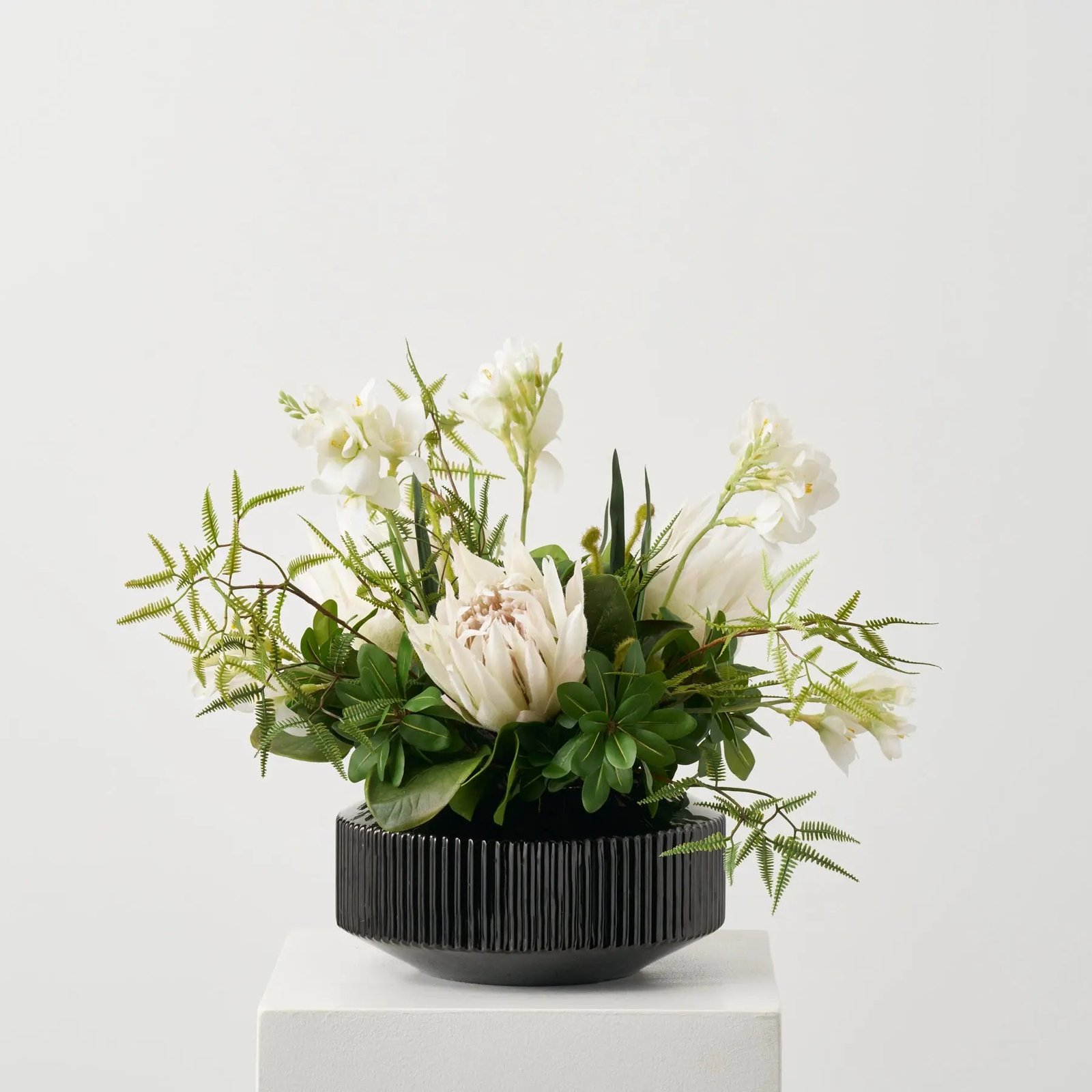 AR1872JungleElegance-LargeWhiteProteaBlooms_WildFern_PittsoporiumTropicaleverydayModernFloralArrangementi_1 Jungle Elegance - Large White Protea Blooms, Wild Fern & Pittosporum Tropical everyday Modern Floral Arrangement in Rounded Black Glass Vase - Image 1